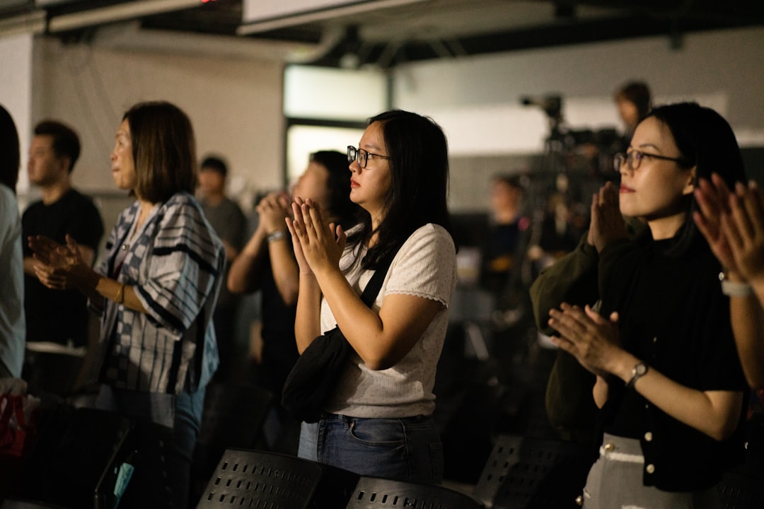 A diverse group of people in an audience clapping their hands together, showing appreciation or recognition for a performance or speech.