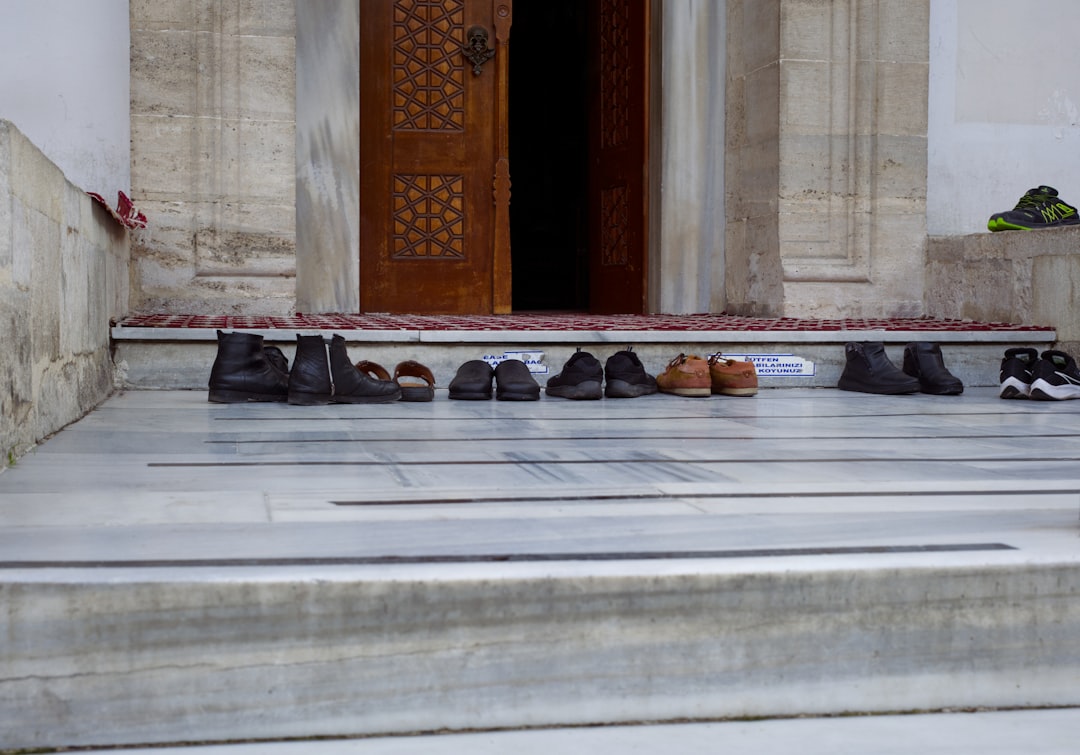 A neatly arranged row of shoes, possibly including slippers, placed at the entrance area (genkan) of a traditional Japanese home, signifying the custom of removing outdoor footwear.