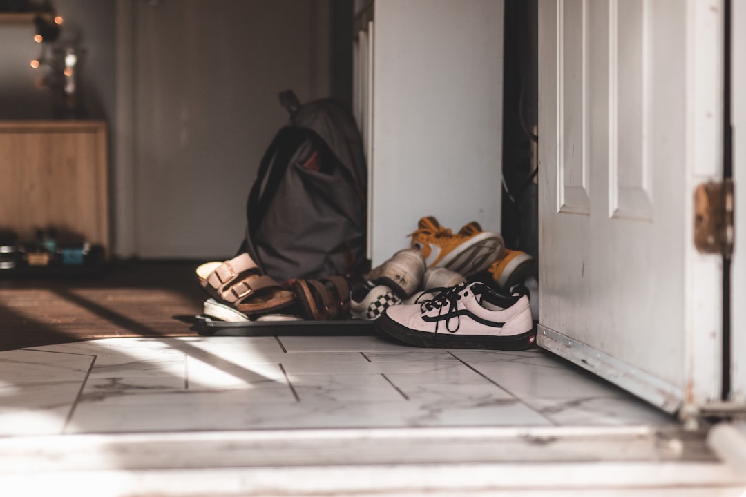 A pair of shoes neatly placed at a home's entrance, possibly with indoor slippers nearby, symbolizing the cultural practice of removing footwear indoors for hygiene and respect.