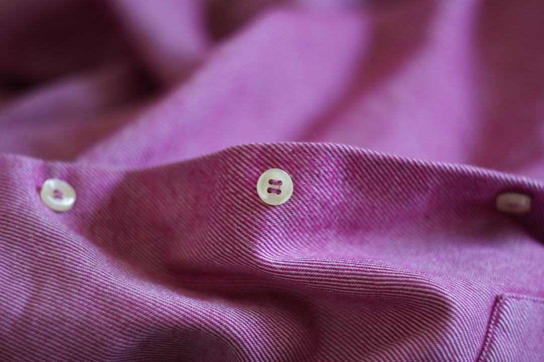 Close-up of neatly sewn shirt buttons on fabric, representing the historical differences in men's and women's button placement and clothing traditions.