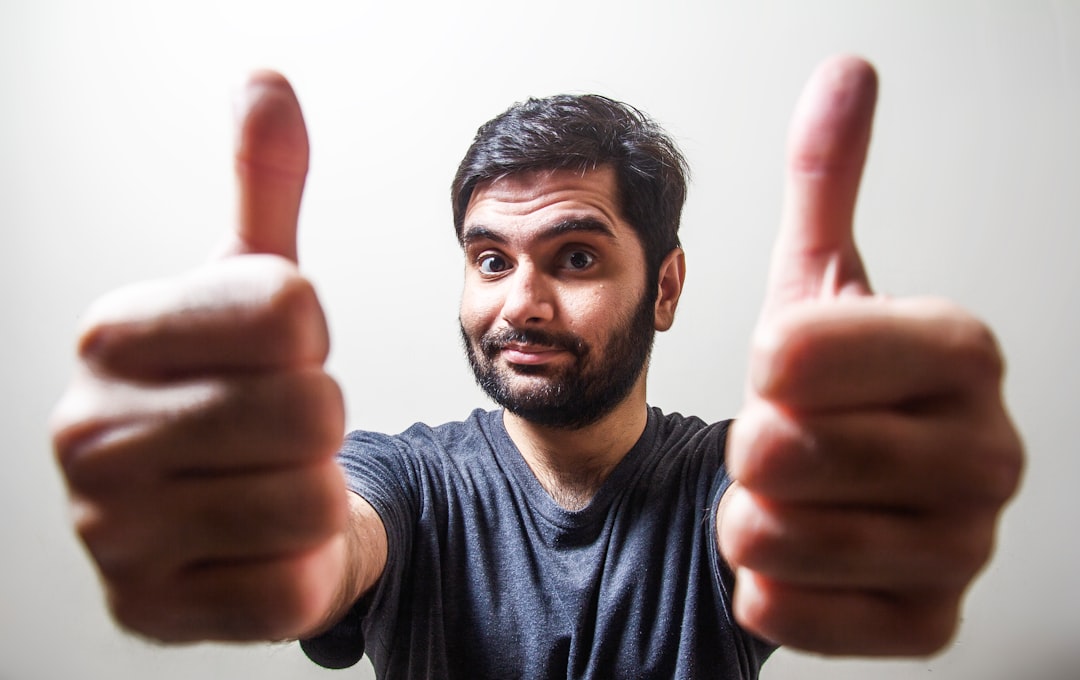 A hand making a thumbs-up gesture with a blurred world map or diverse cultural symbols in the background, illustrating the varying interpretations of this sign across different cultures.