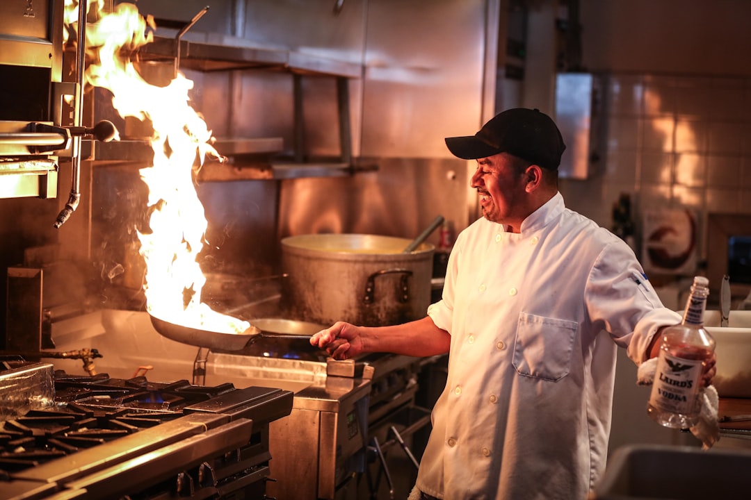Professional chef cooking with high heat in a wok, flames visible, showing expertise in culinary techniques.