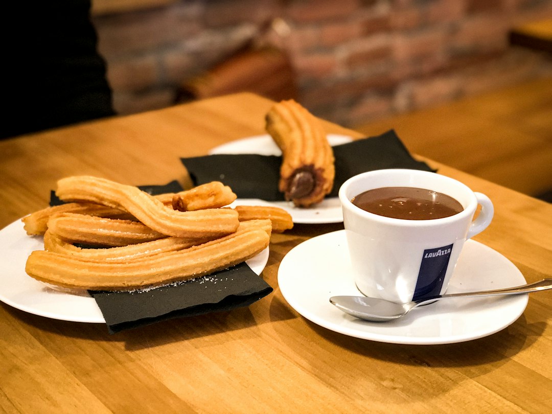 Golden brown churros served with a side of rich, thick hot chocolate in a cafe setting.