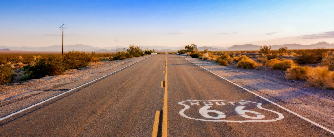 A classic American car driving on Historic Route 66 through a desert landscape, symbolizing adventure and cultural heritage.