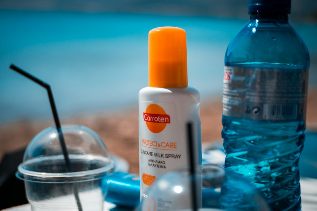 A serene lagoon showing a visible oil film on the water surface, hinting at sunscreen residue and environmental pollution.