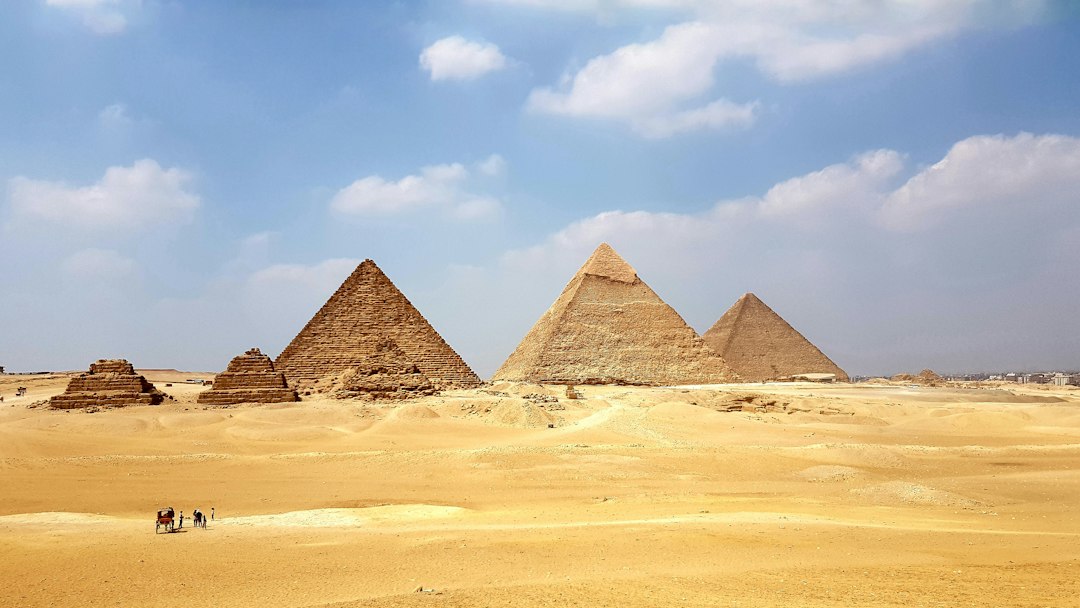 Exterior view of the Grand Egyptian Museum with the Giza Pyramids visible in the background under a clear sky.
